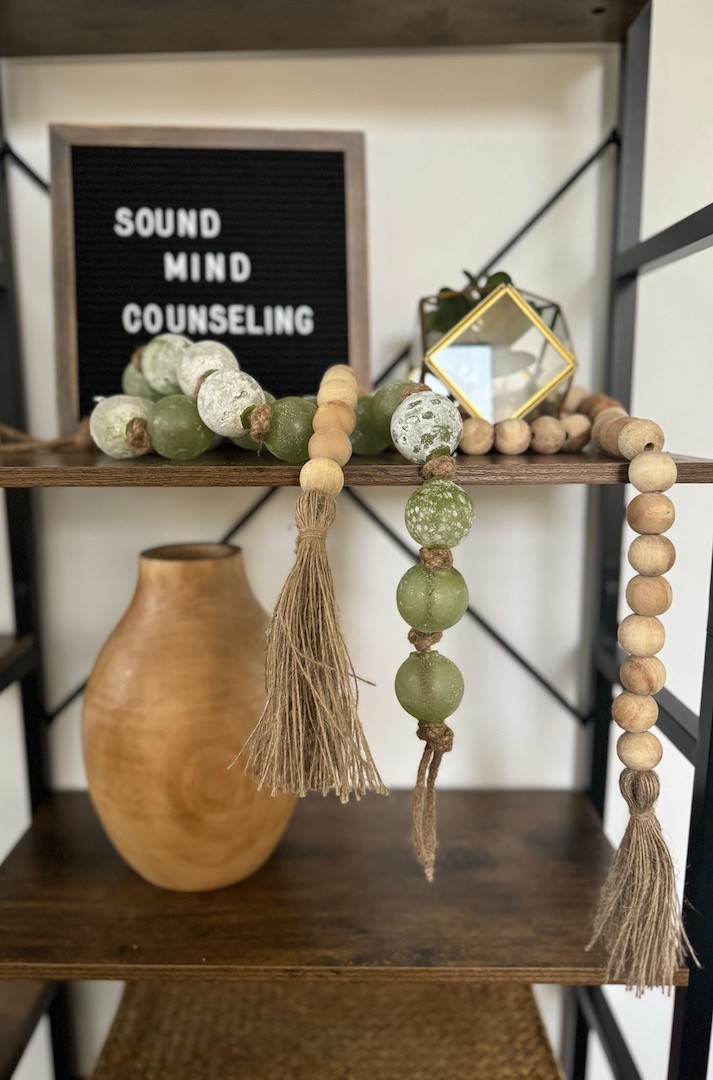 "Sound Mind Counseling" sign sitting on a book shelf with random trinkets next to it